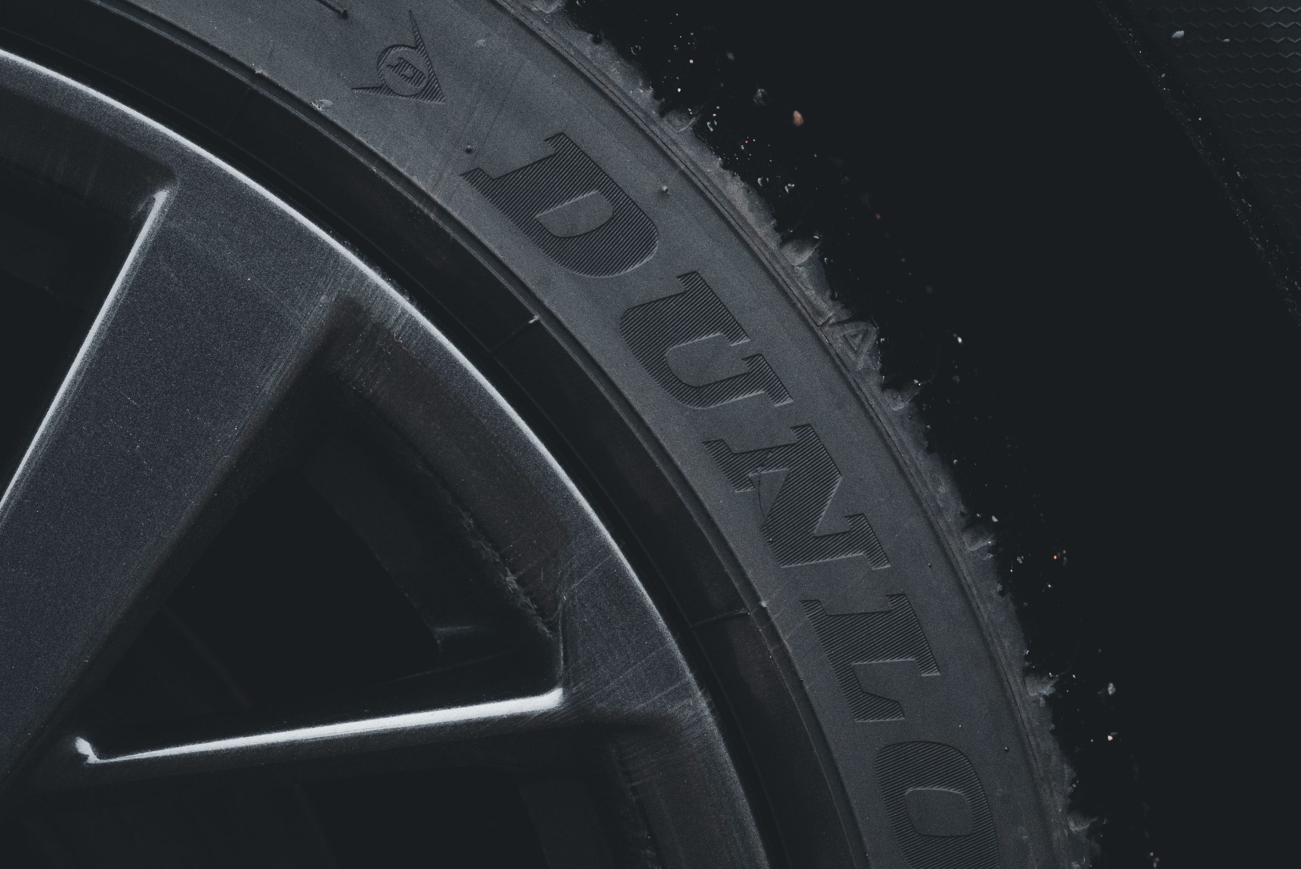 Services Detailed close-up of a Dunlop tire and rim showcasing its texture and brand text.