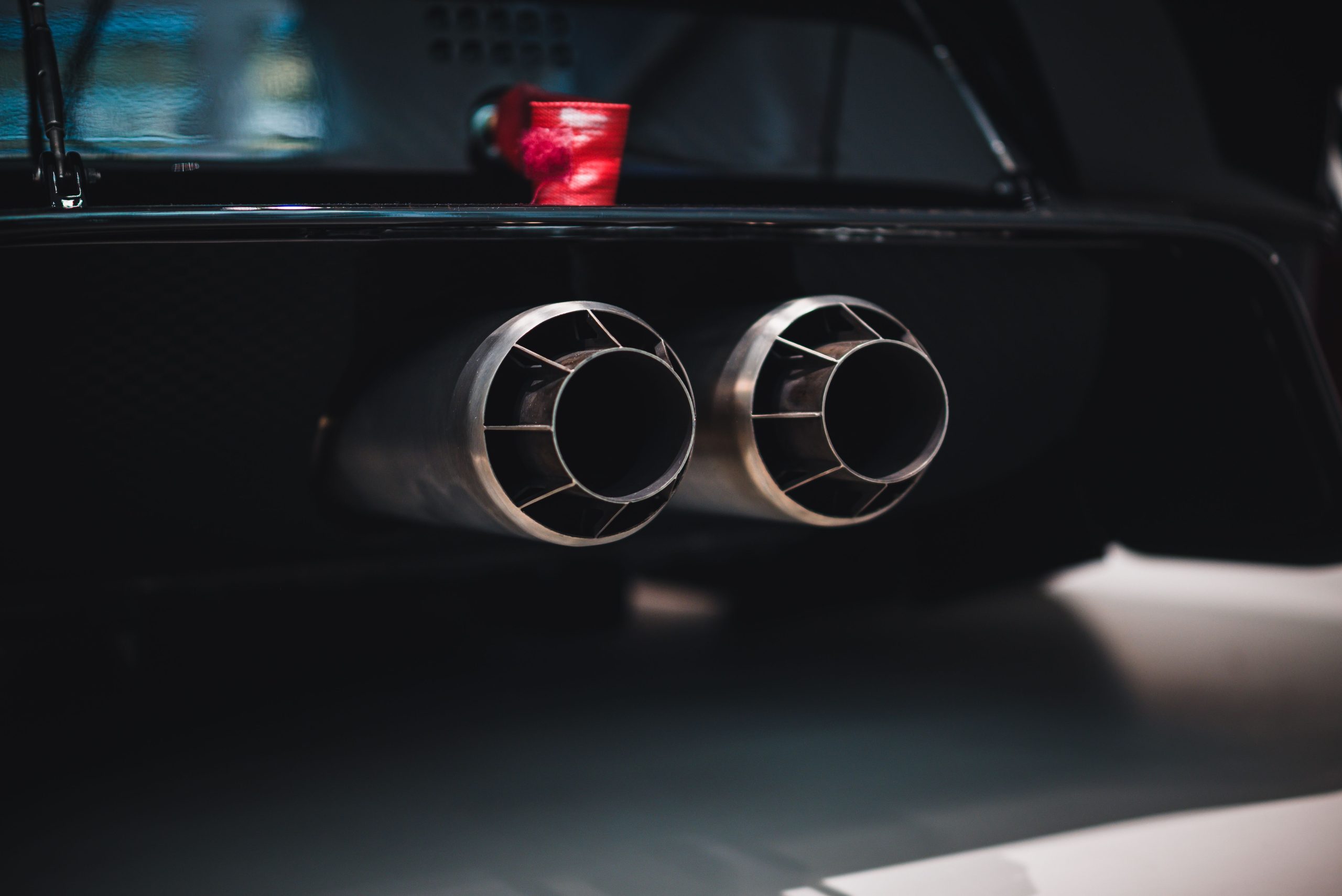 Services Close-up shot of dual exhaust pipes on a sleek car, with a focus on detail and design.