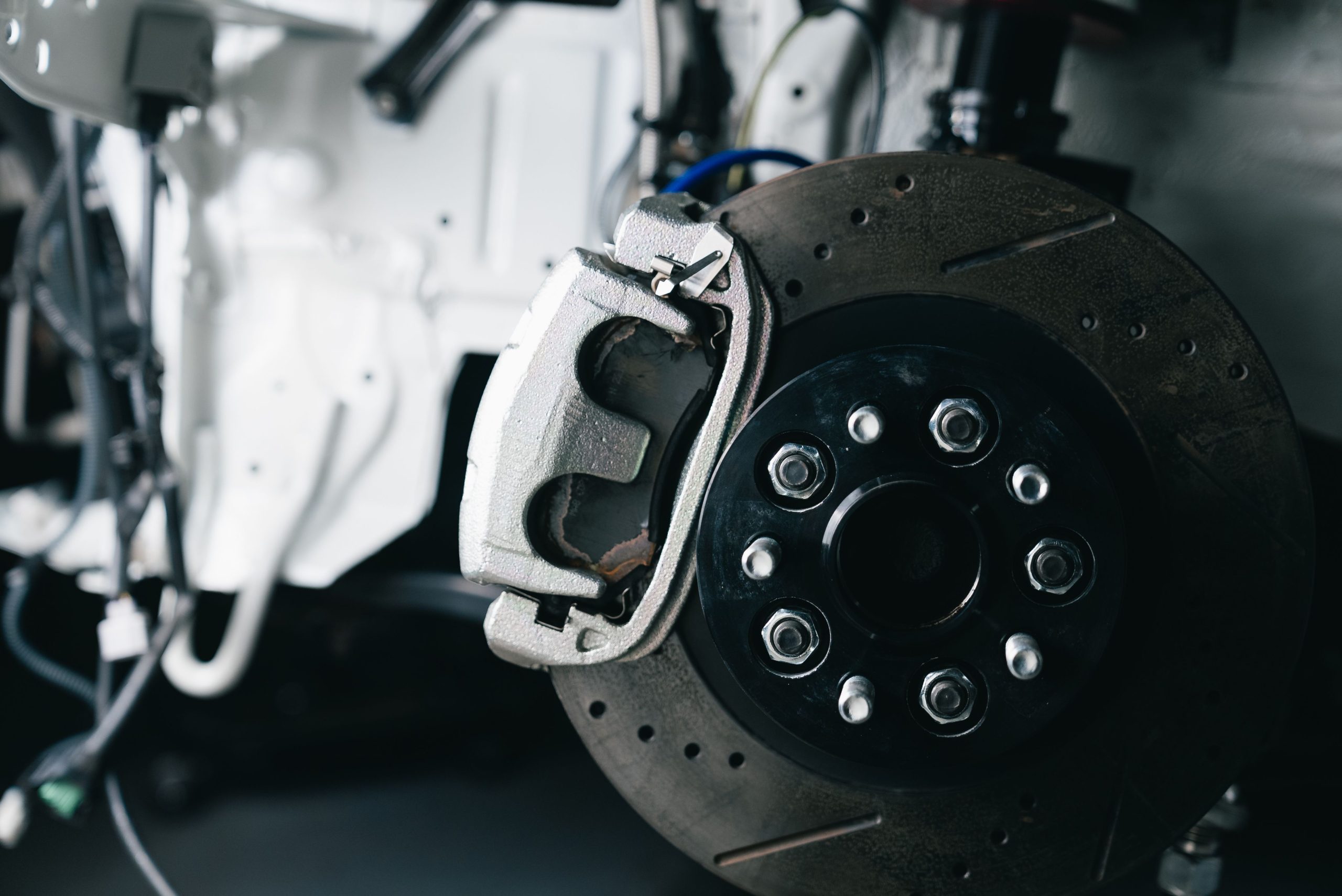 Services Detailed view of a car's brake caliper and disc in a workshop setting.