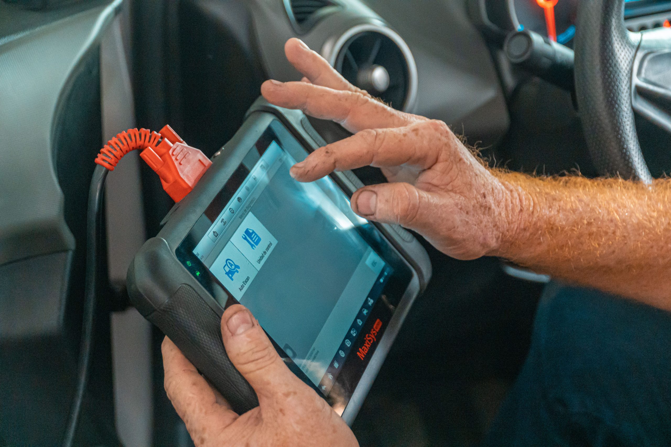 Services Mechanic using a diagnostic tool inside a car to check for engine issues and ensure proper maintenance.