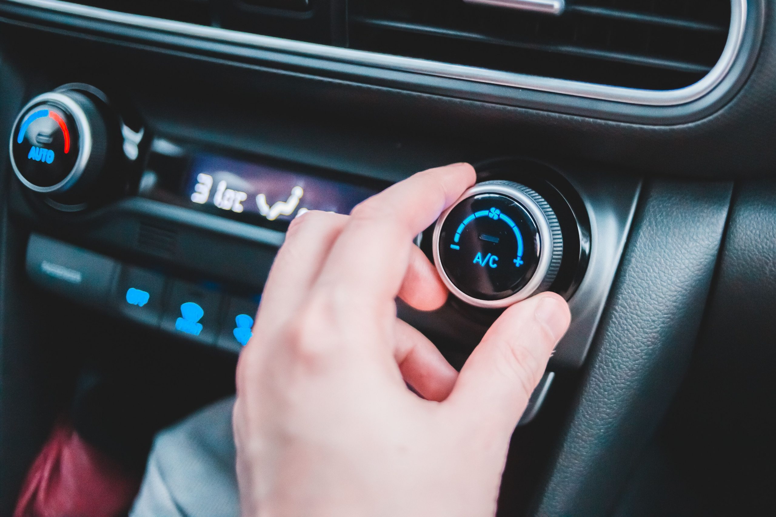 Services Crop anonymous person regulating temperature in car using controller on panel while sitting in car